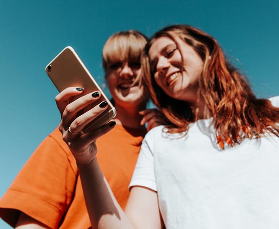 Two girls outdoors using a phone