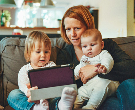 Mom and two kids using a tablet at home.