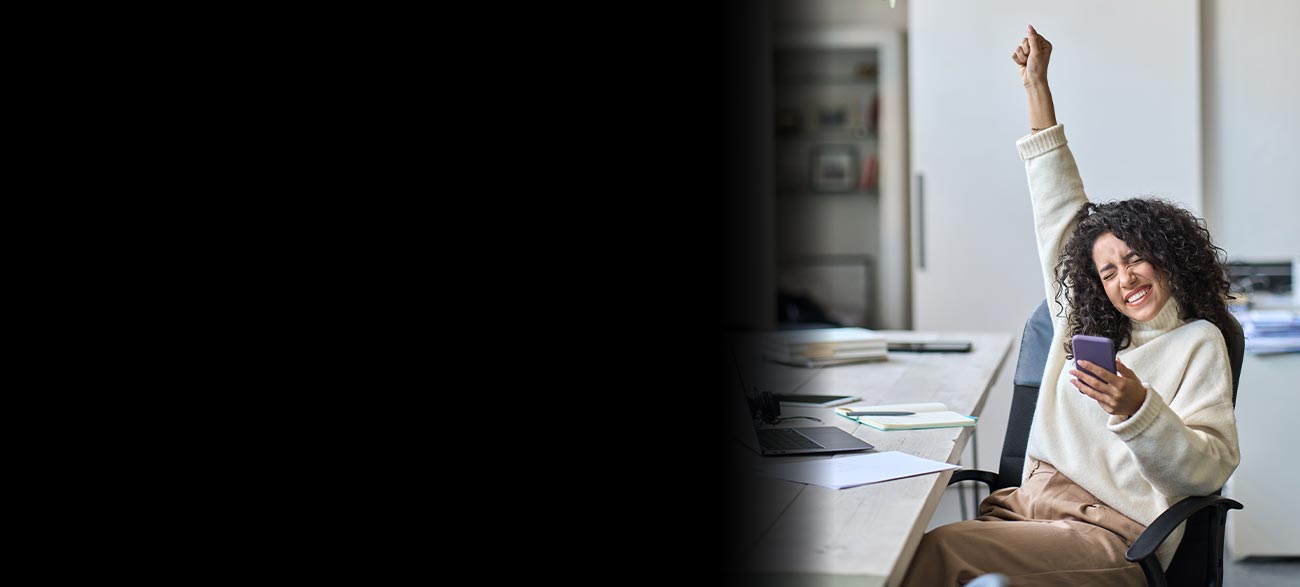 Woman raising hand in excitement looking at phone.
