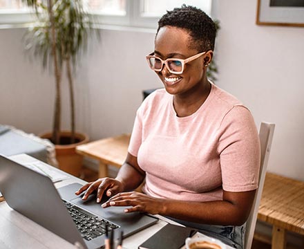 Woman using a laptop at her home office.