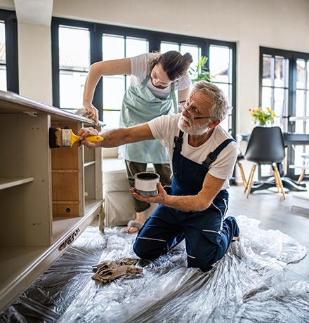 Two people staining their kitchen cabinets.