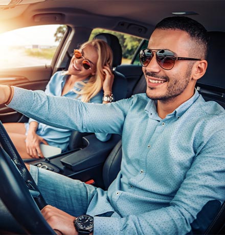 Couple riding in a car with the sun shining through the window.